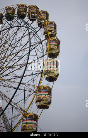Nahaufnahme des mehrfarbigen Riesenrads während Dussehra Mela in Delhi, Indien. Unteransicht des Riesenradschwenkens. Riesenrad mit farbenfrohen Kabinen durin Stockfoto