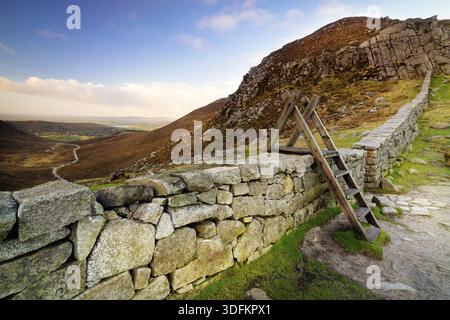 Trauernde Mauer mit Leiter auf der Hare-Lücke, die das schöne Tal mit blauem Himmel und weißen Wolken beaufsichtigt. Mourne Mountains Range in Nordirland Stockfoto