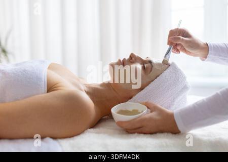 Frau genießt Gesichtsmaske im Spa, Augen geschlossen Stockfoto