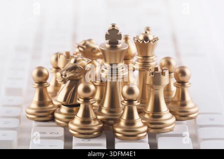 Gruppe luxuriöser goldener Schachfiguren auf weißer Computertastatur Stockfoto