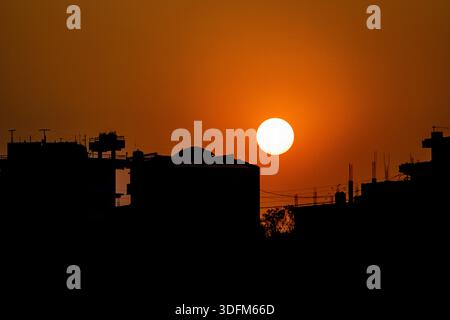 Ein atemberaubender Sonnenuntergang mit einer großen, leuchtend gelben Sonne, die unter den Horizont fällt. Der Himmel ist in warmen Orangen-, Gold- und Weichstiften gemalt Stockfoto
