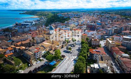 Drohnenfoto von Ortona mit seinem historischen Stadtbild, engen Gassen und alten Gebäuden unter einem leuchtend blauen Himmel mit ein paar weichen weißen Wolken. Stockfoto