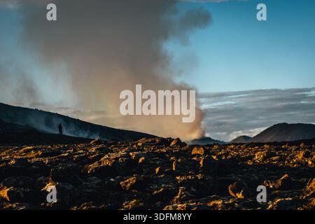 Der Blick auf eine einzelne Figur steht vor dem Hintergrund vulkanischer Rauch, der aus dem Geldingadalir-Ausbruch auf der Halbinsel Reykjanes, Island, Fa aufsteigt Stockfoto