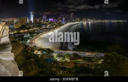 Erhöhter Blick vom Mirador de l'Ermita Verge del Mar in Benidorm bei Nacht, mit Stadtküste, Strand Poniente und ruhigem Meer, Straße und Gebäuden Stockfoto