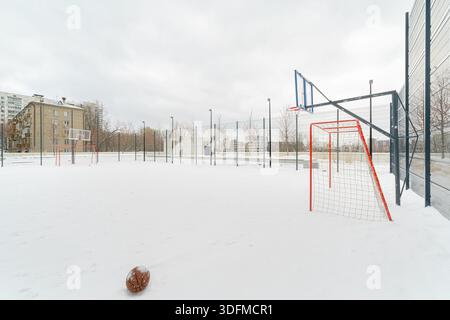 Basketballfeld mit Netz und Toren. Der Platz ist mit Schnee bedeckt. Stockfoto