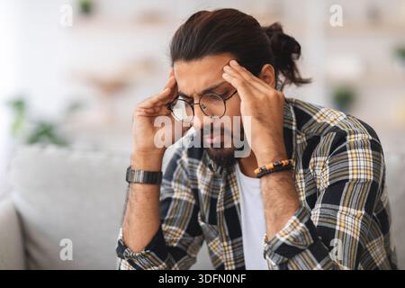 Nahaufnahme eines traurigen arabischen Mannes, der seinen Kopf berührt Stockfoto