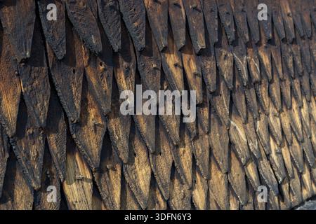 Blick auf verwitterte, überlappende Holzschindeln bilden einen strukturierten Wandteppich aus dunklem Braun und Schwarz, der auf die alte Architektur der Stabkirche Eid hinweist Stockfoto