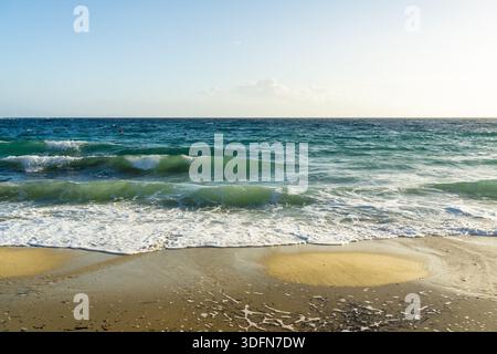 Blick auf die ruhigen türkisfarbenen Wellen, die sanft den goldenen Sand unter einem ruhigen blauen Himmel küssen und zu friedlicher Betrachtung einladen, Mykonos, Mykonos, Griechenland Stockfoto