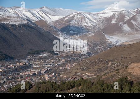 Panoramablick auf Goris in Armenien, eingebettet zwischen Bergen mit schneebedeckten Gipfeln, mehrschichtigen Hügeln, städtischen Gebäuden und klarem Winterlicht Stockfoto