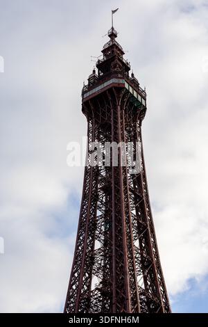 Eine Nahaufnahme eines hohen, gitterartigen Eisenturms vor einem bewölkten Himmel. Der Turm ist überwiegend rötlich-braun. Stockfoto