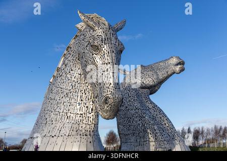 Zwei massive, aufwändig konstruierte Pferdekopfskulpturen aus Edelstahl stehen vor einem hellblauen Himmel. Ihre reflektierenden Oberflächen und Details entsprechen Stockfoto