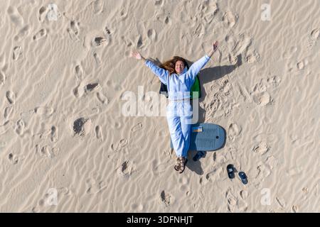Luftfrau auf gewelltem Sand mit Bodyboard in den Dünen von Fuerteventura Stockfoto