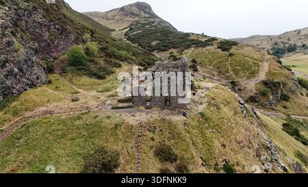Die Ruinen der St. Anthony’s Chapel an den Hängen des Arthur’s Seat in Edinburgh. Die mittelalterlichen Steinreste überblicken die umliegenden Hügel und Wanderwege Stockfoto