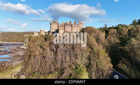 Blick aus der Vogelperspektive auf Culzean Castle, dramatisch über bewaldeten Klippen an der Küste von Ayrshire mit Blick auf den Firth of Clyde, Schottland. Tagsüber. Stockfoto