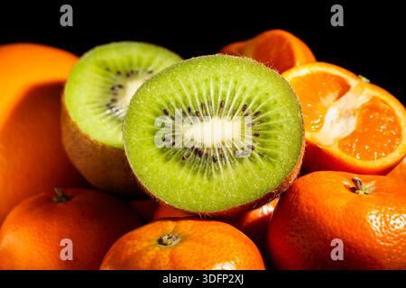 In Scheiben geschnittene Kiwi-Mandarinen auf schwarzem Hintergrund Stockfoto