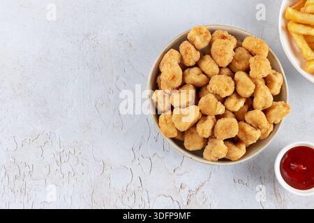 Popcorn-Huhn mit Ketchup und Pommes frites auf weißem Teller, auf weißem Hintergrund. Fast Food. Top-Blick. Kopierbereich Stockfoto