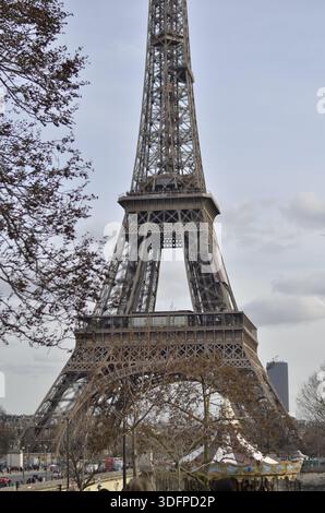 Blick auf den Eiffelturm in Paris von unten gesehen, von Bäumen eingerahmt, ein berühmtes Wahrzeichen in einer ruhigen Tagesszene. Stockfoto