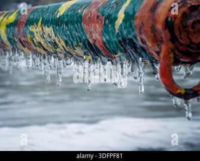 Nahaufnahme eines bunten Metallzauns mit Eis und Frost. Stockfoto