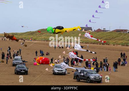 Riesige aufblasbare Drachen fliegen während eines Drachenfestes in Lytham St. Annes über den Strand, bei dem die Menschenmassen die Veranstaltung am Meer genießen. Stockfoto