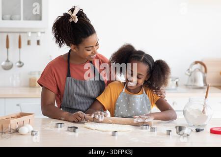 Liebevolle Mutter hilft ihrer Teenager-Tochter beim Backen Stockfoto