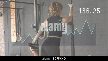 Halteständer, Frau in schwarzer Aktivkleidung zieht Fuß an die Gesäßmuskulatur im Fitnessstudio, mit Digital 136 Stockfoto