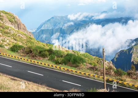 Atemberaubende Aussicht auf den Aussichtspunkt Lombo do Mouro in Madeira, Portugal, fängt eine malerische Bergstraße ein, die scheinbar zwischen Himmel und Erde schwebt Stockfoto