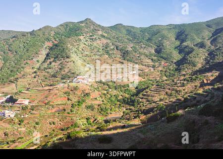Panoramablick auf das abgelegene Dorf Las Portelas in den Bergen Teno auf Teneriffa, eingebettet in ein üppiges, terrassenförmiges Tal. Traditionelle weiße Häuser Stockfoto