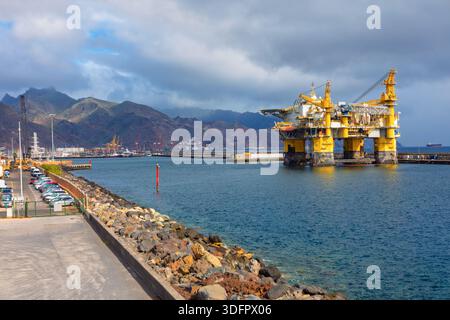 Offshore-Bohrgerät im Hafen angedockt mit einer felsigen Küstenlinie im Vordergrund. Die Tauchanlage befindet sich im Hafen von Santa Cruz de Tenerife Stockfoto