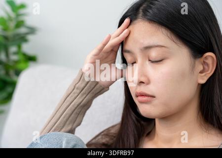 Leiden Sie verzweifelt und gestresst an Kopfschmerzen, weil Schmerzen und Migräne. asiatischer junger Mann, der Migräne bei der Arbeit, Hirntumor, hohe Cholesterin Stockfoto
