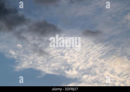 Genießen Sie einen atemberaubenden Blick auf Wolken in verschiedenen Farben vor einem dunklen Himmel, ideal für stimmungsvolle Stimmungen Stockfoto