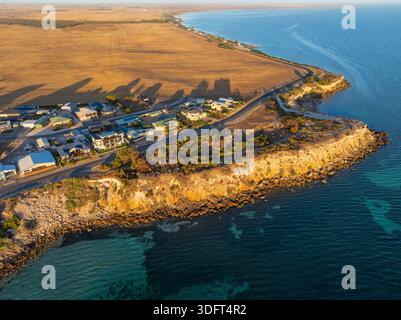 Aus der Vogelperspektive des Morgenlichts in einer kleinen Küstenstadt zwischen trockenem Ackerland und einer felsigen Klippe am Point Turton auf der Yorke Peninsula in Südaustralien. Stockfoto