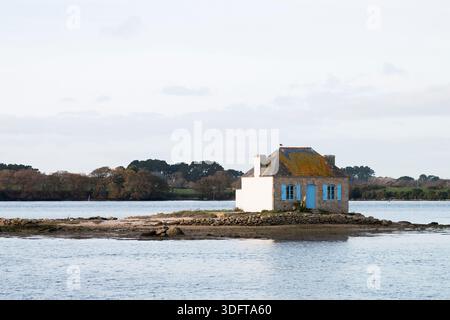 Ein Haus mit blauem Fenster, umgeben von der Seatide, auf der Insel Saint Cado in der Stadt Belz in der Bretagne, Frankreich Stockfoto