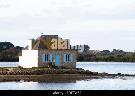 Ein Haus mit blauem Fenster, umgeben von der Seatide auf der Insel Saint Cado in der Stadt Belz in der Bretagne, Frankreich Stockfoto