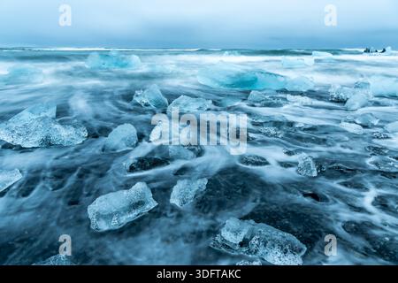 Blick auf durchscheinende Eisdiamanten, die auf dem schwarzen Sand verstreut sind, getragen von der sanften Umarmung der Flut am Diamond Beach, Hofn, Vatnajokull, Island. Stockfoto