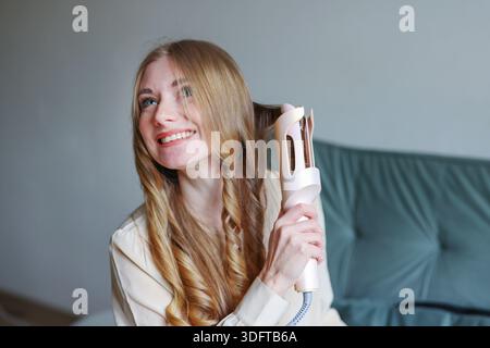 Attraktive Frau, die zu Hause mit entspanntem Lächeln und lässigem Outfit das Styling genießt Stockfoto