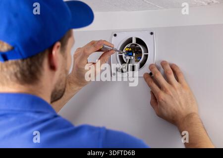 HLK-Servicemitarbeiter, der am Abluftventilator im Badezimmer arbeitet Stockfoto