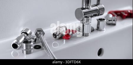 Klempnerwerkzeuge und Chromarmaturen am Waschbecken im Badezimmer. Sanitär- und Reparaturarbeiten Stockfoto