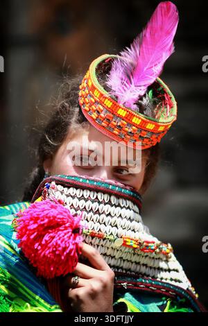 Kalash, Pakistan - 24. Dezember 2025: Blick auf das Gesicht einer Kalash-Frau mit lebendigem traditionellem Kopfschmuck und markantem perlenbesetztem Kragen, Eyes Peer Stockfoto