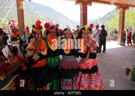 Kalash, Pakistan - 24. Dezember 2025: Blick auf Kalashi-Frauen, die in lebendiger traditioneller Kleidung verziert sind, versprühen Freude vor der Kulisse des Berges Stockfoto