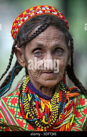 Kalash, Pakistan - 24. Dezember 2025: Blick auf eine ältere Kalash Frau mit geflochtenen Haaren, verziert mit einem lebendigen Kopfschmuck und bunten Perlen Halsketten, Stockfoto