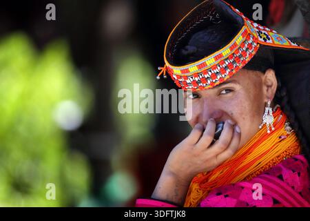 Kalash, Pakistan - 24. Dezember 2025: Blick auf eine Frau aus Kalash, die in lebendiger traditioneller Kleidung gehalten ist, ihr warmes Lächeln und ihr komplizierter Kopfschmuck ein Zeugnis ist Stockfoto
