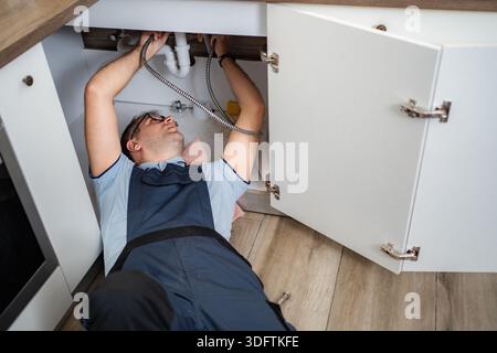 Klempner befestigen Küchenspüle Abfluss unter Schrank Stockfoto