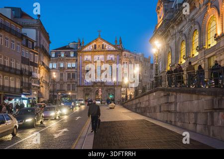 Porto, Portugal - 26. November 2017: Blick auf die beleuchtete Fassade der Kirche Igreja dos Congregados, die in der Dämmerung ein goldenes Licht auf die Straße wirft Stockfoto