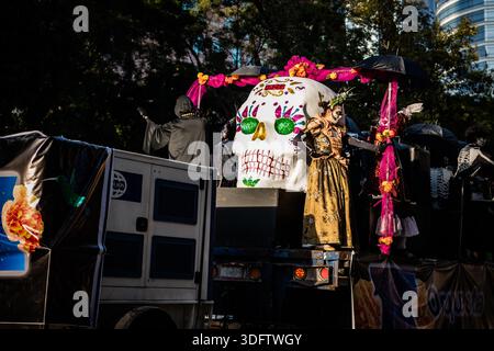 Mexiko-Stadt, Mexiko - 4. November 2023: Blick auf einen pulsierenden Tag der Toten Parade, geschmückt mit einem großen Schädel, dessen gemaltes Gesicht gegen t fällt Stockfoto