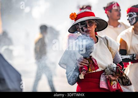 Mexiko-Stadt, Mexiko - 4. November 2023: Blick auf einen Straßenkünstler bei der Day of the Dead-Parade, geschmückt in leuchtendem Rot und weiß, in dem Rauch bläst Stockfoto