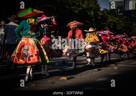 Mexiko-Stadt, Mexiko - 4. November 2023: Blick auf Tänzer in lebendigen, wirbelnden Kleidern und übergroßen Sombreros, ein Kaleidoskop von Farben gegen die Stadt Stockfoto