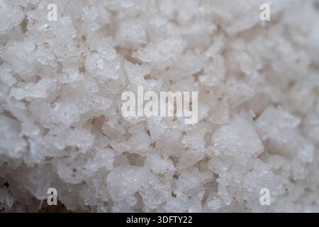 Nahaufnahme von groben weißen Meersalzkörnern. Detaillierte kristalline Textur des organischen Minerals für kulinarische, Spa- und Gesundheitskonzepte. Stockfoto