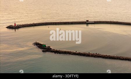 Drohnenblick auf den Morgensonnenaufgang über einer ruhigen Meeresbucht Stockfoto