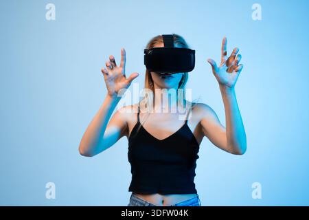 Frau mit Virtual-Reality-Headset mit Handgesten, immersiver VR-Technologie und futuristischem digitalem Erlebnis Stockfoto