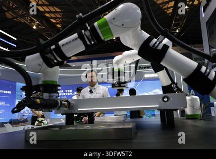 (260114) -- PEKING, 14. Januar 2026 (Xinhua) -- Ein Mitarbeiter schaut zu, wie kollaborative Roboter während der 11. China (Shanghai) International Technology Fair (CSITF) im ostchinesischen Shanghai am 11. Juni 2025 die Montage und Überprüfung von Batteriepaketen demonstrieren. (Xinhua/Fang Zhe) Stockfoto